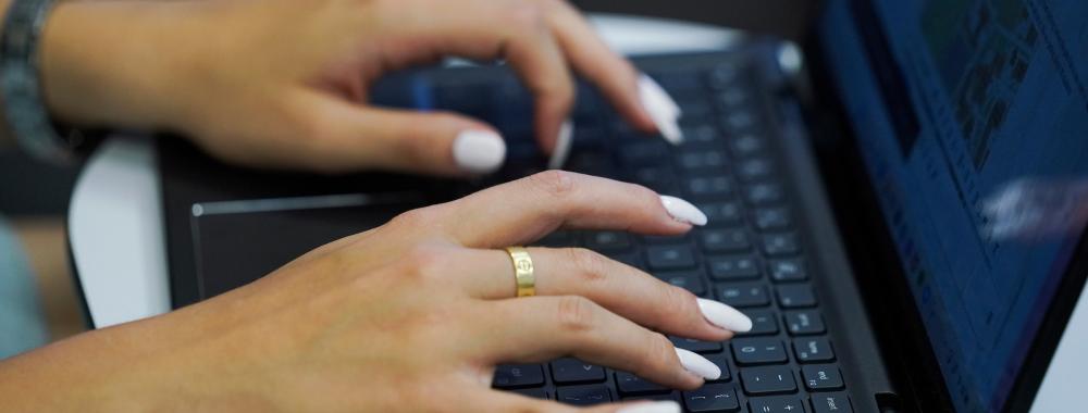 A student with white nails types on a laptop.