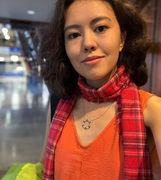 Smiling young woman indoors wearing orange top and red plaid scarf
